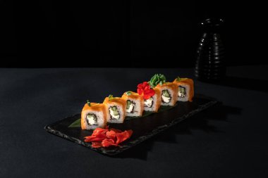 Taze balıklı suşi rulosu, avokado, siyah arka planda krem peynir. Suşi menüsü. Japon yemeği..