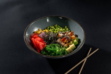 Füme yılan balığı, pilav, avokado, edamame fasulyesi, salatalık ve siyah arka planda turp.