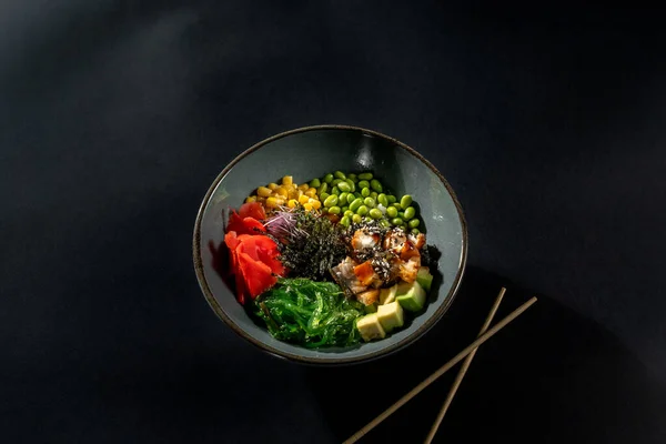 Füme yılan balığı, pilav, avokado, edamame fasulyesi, salatalık ve siyah arka planda turp.