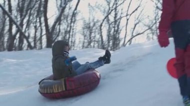 Dışarıda karla oynayan gülümseyen çocuklar. Çocuk tatilde ve tatilde arkadaşlarıyla kış parkında eğleniyor. Duygu, mutluluk, yaşam tarzı konsepti. Yokuşta snowboardcu