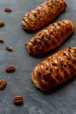 Bakery pastries with pecan on grey table, background. Freshly cooked bakery. Home cooked bakery for morning breakfast. Copy space. Vertical shot. Selective focus