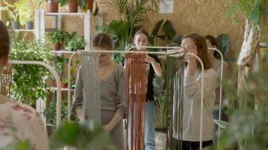 Sanat dersine katılan bir grup kadın. Bayan öğrenciler ve öğretmen birlikte atölyede Boho stilinde ev dekorasyonu yapıyorlar. Sanat okulu stüdyosunda el yapımı makrome örüyor. Yaratıcılık, insanların eğitimi