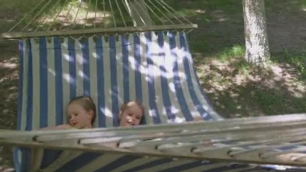 夏のアウトドアを楽しむ小さな女の子 キャンプでハンモックに寝そべっている子供たち 笑顔で笑ってる 幸福と団結の概念 — ストック動画