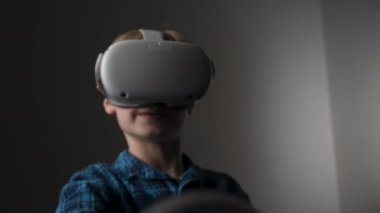 Çocuk VR kulaklıkla oyun oynuyor. Evde iyi vakit geçiriyorum. Sanal gerçekliği izole etmek. VR kulaklık takan, elini hareket ettiren ve havaya dokunan bir çocuk. Dijital eğitim ya da sanal gerçeklik öğrenme kavramı