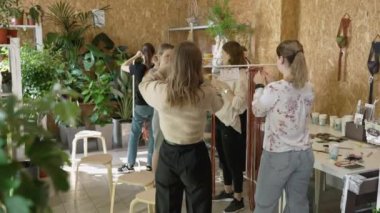Sanat dersine katılan bir grup kadın. Bayan öğrenciler ve öğretmen birlikte atölyede Boho stilinde ev dekorasyonu yapıyorlar. Sanat okulu stüdyosunda el yapımı makrome örüyor. Yaratıcılık, insanların eğitimi