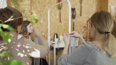 Sanat dersine katılan bir grup kadın. Bayan öğrenciler ve öğretmen birlikte atölyede Boho stilinde ev dekorasyonu yapıyorlar. Sanat okulu stüdyosunda el yapımı makrome örüyor. Yaratıcılık, insanların eğitimi