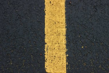 Yüzey pürüzsüz asfalt pürüzsüz koyu gri yol üzerinde sarı çizgi ve küçük kaya dokusu Üst Görünümü
