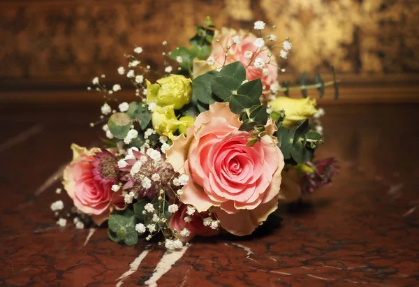 Eski bir masanın üzerinde bir buket çiçek.