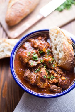 Geleneksel acı biber güveci. Koyu ahşap bir yeraltı ekmeğiyle birlikte.