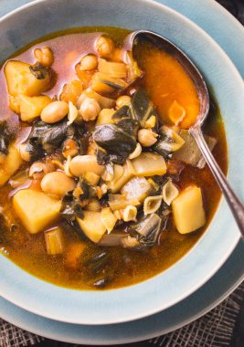 Fasulyeli, patatesli, domuz göbekli, koyu renk bir İspanyol pazı yahnisi.