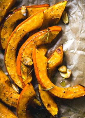 Koyu bir ortamda kavrulmuş hokkaido kabağı dilimleri dolu ahşap bir tepsi