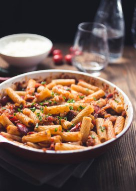 Koyu ahşap arka planda kırmızı soslu ev yapımı makarna tabağı.