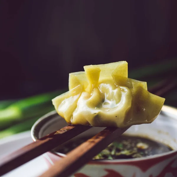 Domuz etiyle dolu bir tabak dolusu gevrek gyoza köftesi ve koyu bir tabakta çekilmiş yeşil kuşkonmazla servis edilmiş.