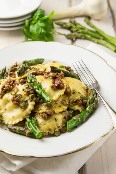 Beyaz bir tabak ravioli, pesto ve kuşkonmaz.