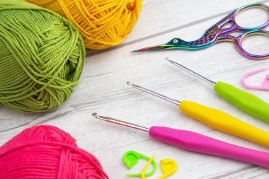 Üç örgü kancası, makas ve dikiş izleriyle düzenlenmiş üç iplik izi.