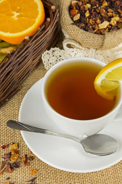 Taza caliente de té, hojas de hierbas y frutas maduras — Foto de Stock