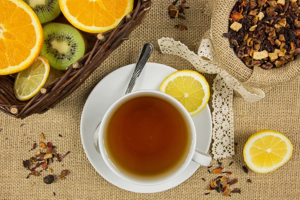 Taza caliente de té, hojas de hierbas y frutas maduras — Foto de Stock