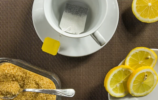 Çay bardağı, dilim limon ve kahverengi şeker — Stok fotoğraf