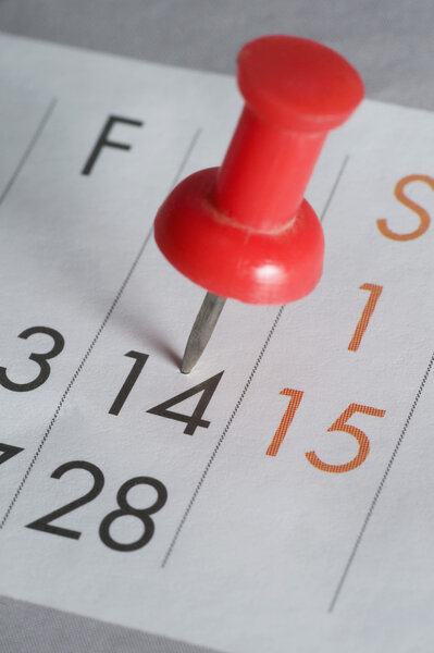 Close-up of a thumbtack on the 14th date of a calendar