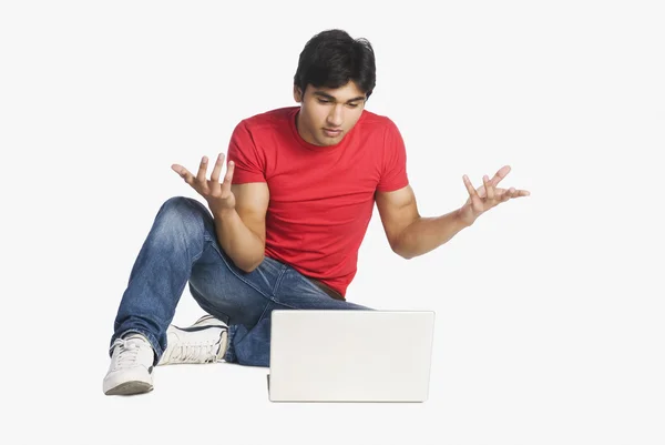 Man gesturing in front of a laptop — Stock Photo, Image