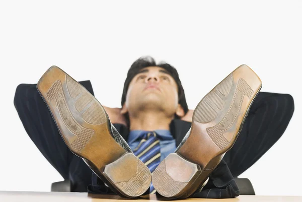 Empresário com os pés em cima de uma mesa — Fotografia de Stock