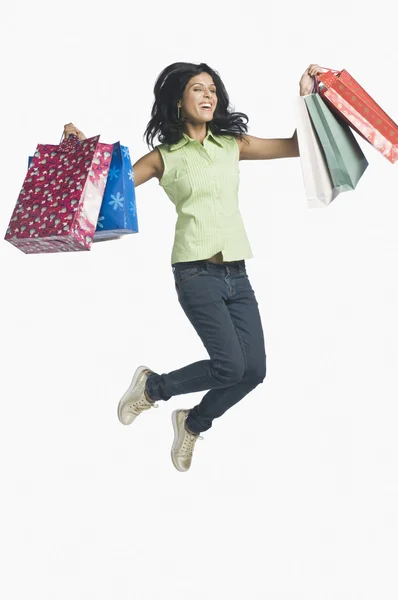 Mulher carregando sacos de compras e salto — Fotografia de Stock