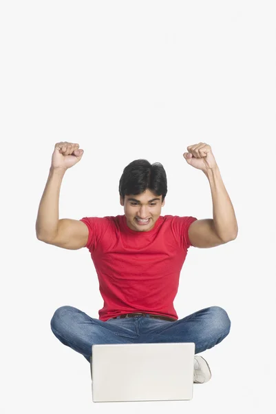 Homem sentado na frente de um laptop e sorrindo — Fotografia de Stock