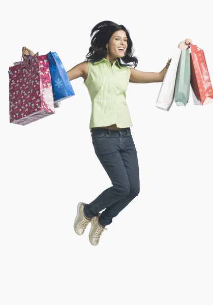 Mulher carregando sacos de compras e salto — Fotografia de Stock