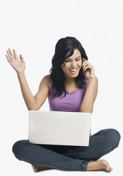 Woman with a laptop and talking on a mobile phone — Stock Photo, Image