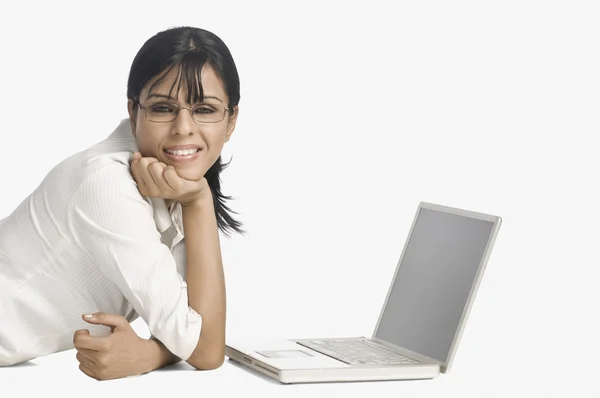 Mulher deitada na frente de um laptop e sorrindo — Fotografia de Stock