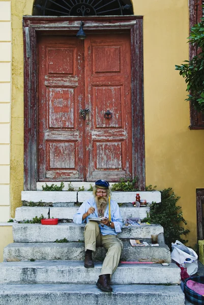 Man sitting on steps and painting — Stock Photo, Image