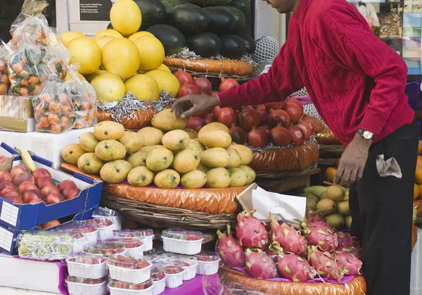 Uomo che sceglie frutta in una bancarella del mercato — Foto Stock