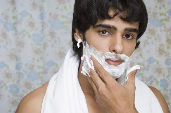 Homem aplicando creme de barbear em seu rosto — Fotografia de Stock