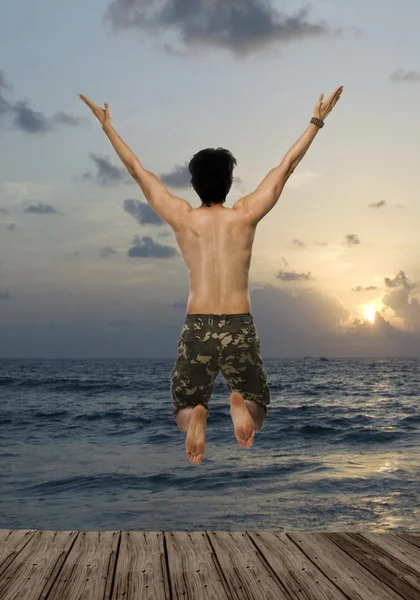 Man jumping with joy over a pier — Stok fotoğraf