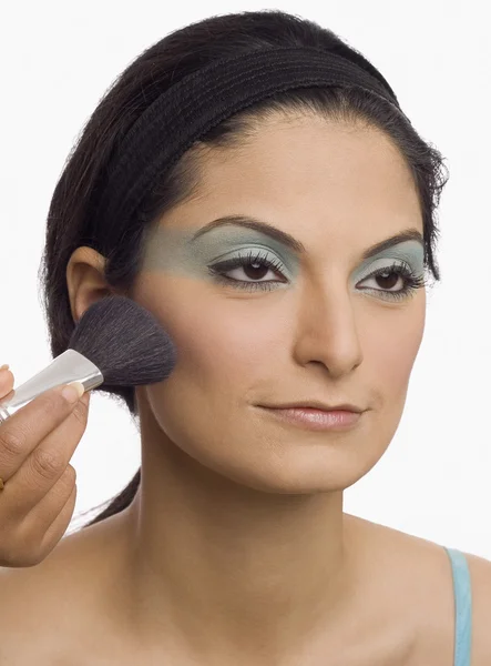 Mão aplicando pincel de maquiagem no rosto de uma jovem — Fotografia de Stock