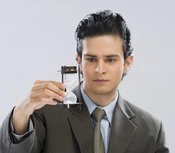 Empresario mirando un reloj de arena — Foto de Stock