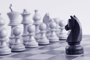 Black knight facing white chess pieces clipart