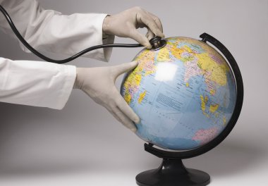 Hands examining a globe with a stethoscope clipart