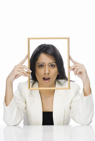 Businesswoman looking through a picture frame — Stock Photo, Image