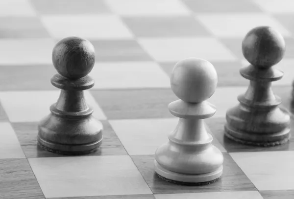 Šachy-bílý pěšec v blízkosti dvou černých šachy figurkami — Stock fotografie