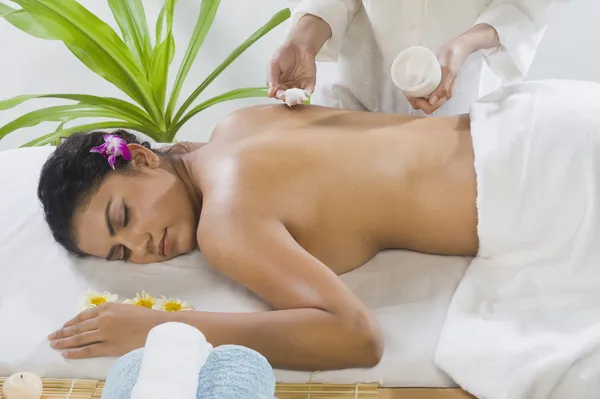 Massage therapist applying massage cream on a young woman's back — Stock Photo, Image