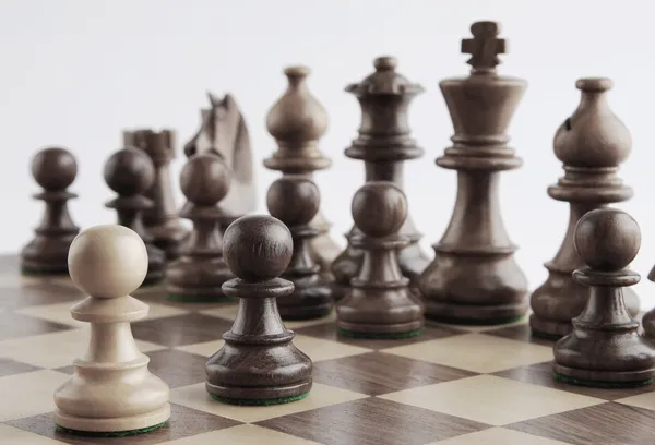 White pawn facing black chess pieces — Stock Photo, Image