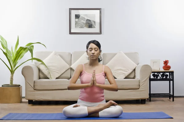Женщина медитирует в гостиной — стоковое фото
