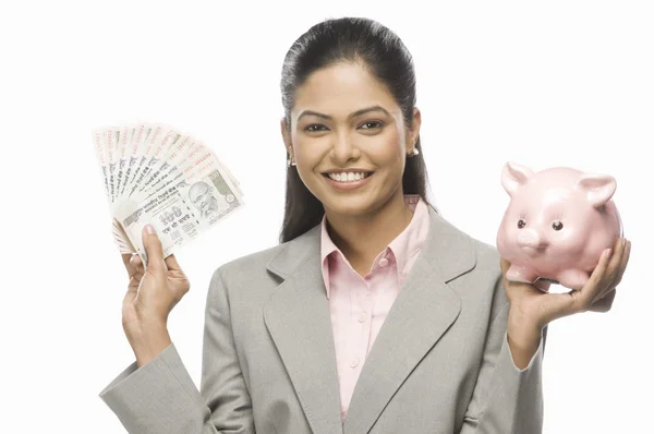 O femeie de afaceri care arată bani şi o bancă de porci — Fotografie, imagine de stoc
