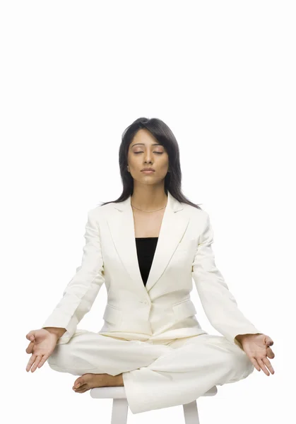 Businesswoman meditating on a stool — Stock Photo, Image