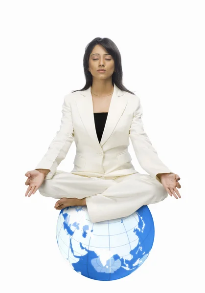 Businesswoman meditating on a globe — Stock Photo, Image