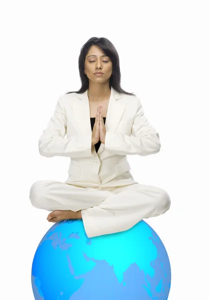Бизнесвумен медитирует на глобусе — стоковое фото