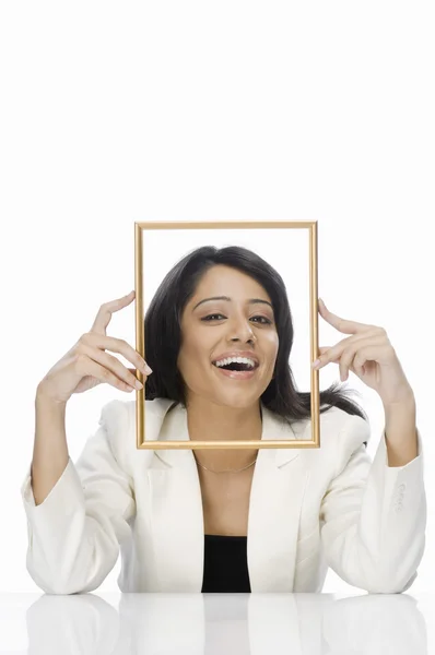 Mujer de negocios mirando a través de un marco de imagen — Foto de Stock