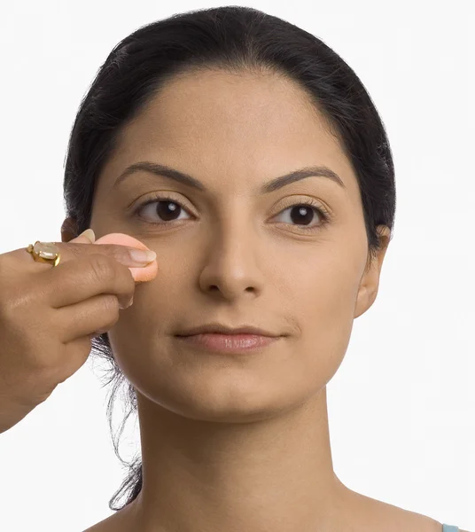 Mão aplicando pó sopro no rosto de uma jovem mulher — Fotografia de Stock