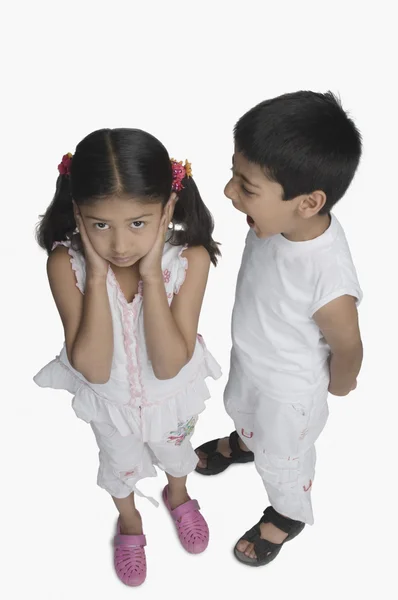 Menina cobrindo seus ouvidos enquanto seu irmão fala — Fotografia de Stock